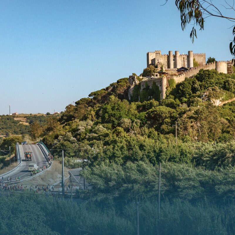 Walking group crossing bridge outside Óbidos castle surrounded by nature
